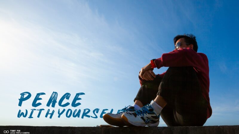 A man sitting on top of a cement wall